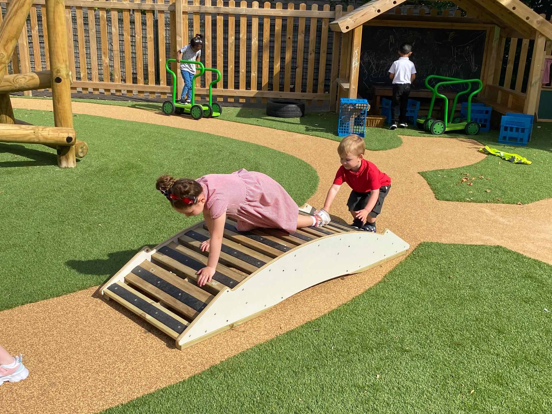 2 children climbing across the play bridge walkway, they are both crawling