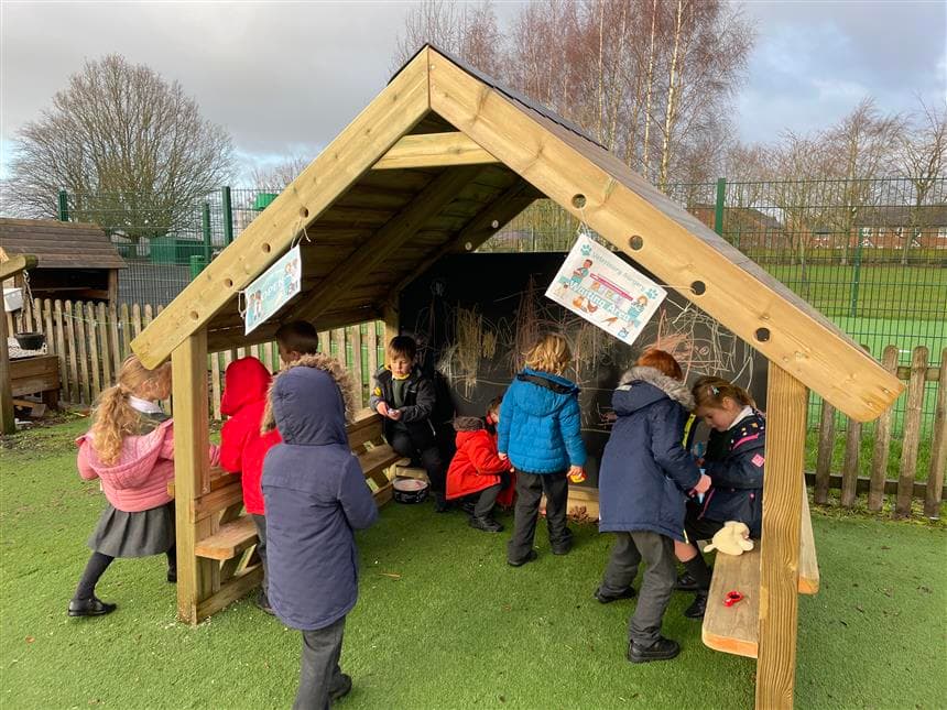 A group of children playing in their playhouse in the playground