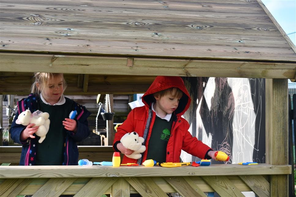 2 young children playing vets in their playhouse