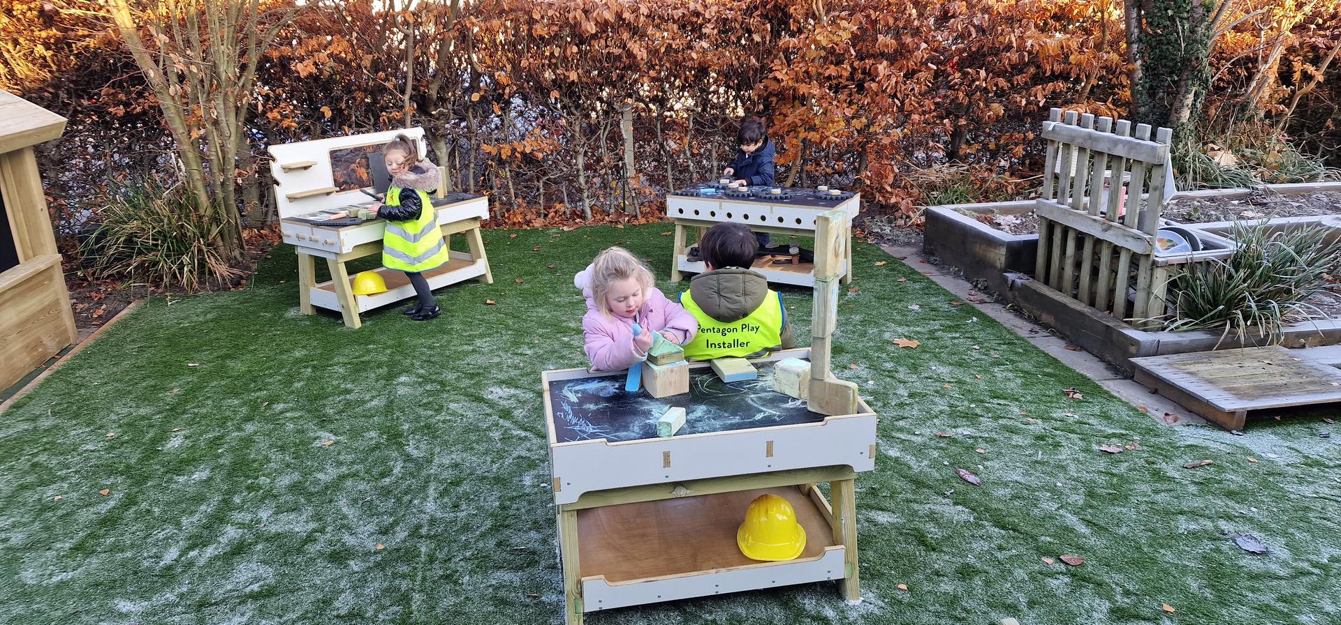 children using the work bench and construction table in their playground
