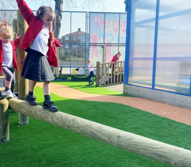 A young girl balancing on the balance beam in her school playground
