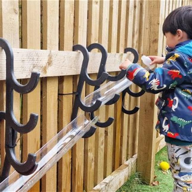 A young boy playing with the water channel hooks in his playground