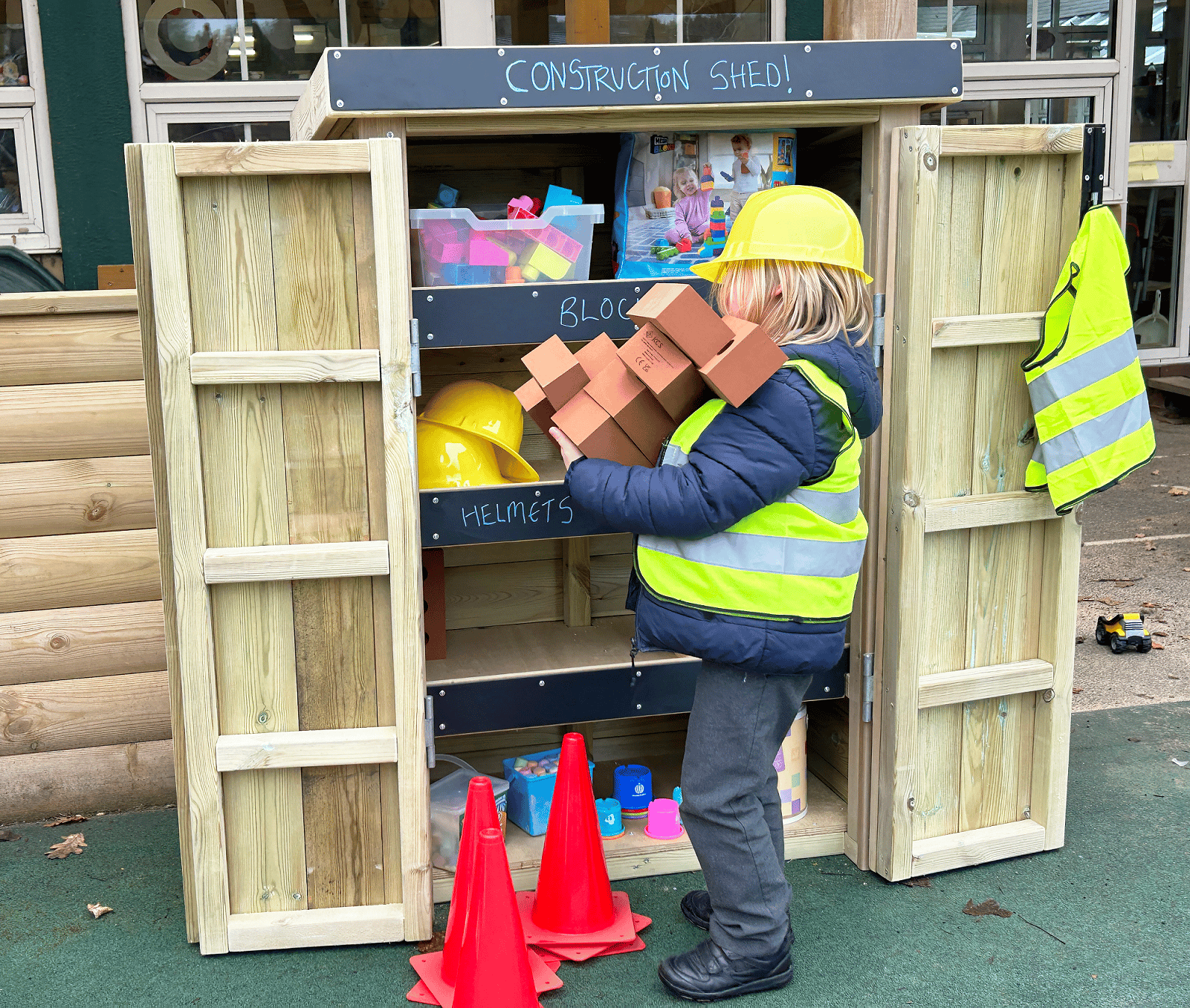 A school boy taking play equipment out of a wooden Acorn Self Select Store