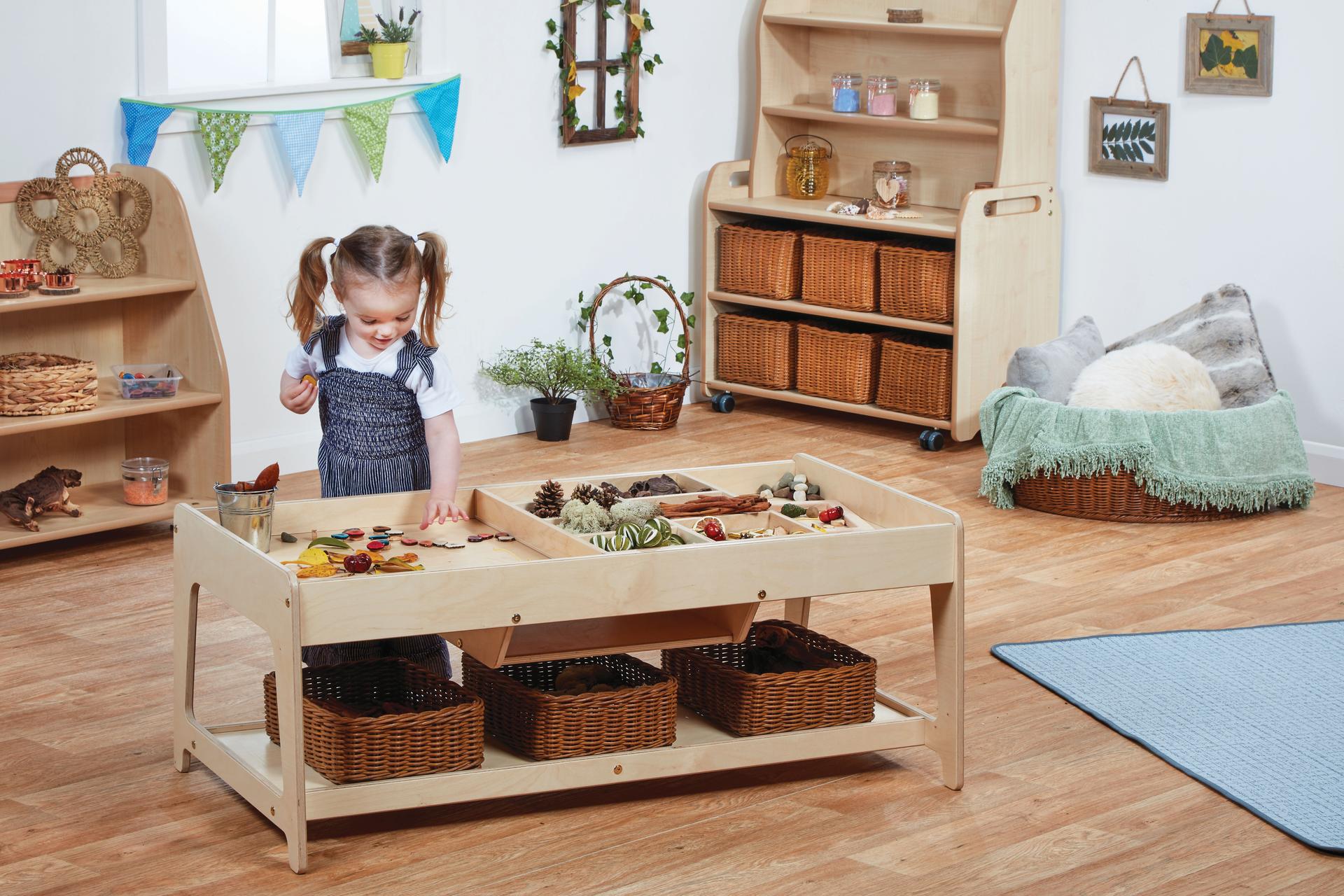 A young girl sorting different small world resources on an Investigative Play Table with 4 Baskets, in a classroom.