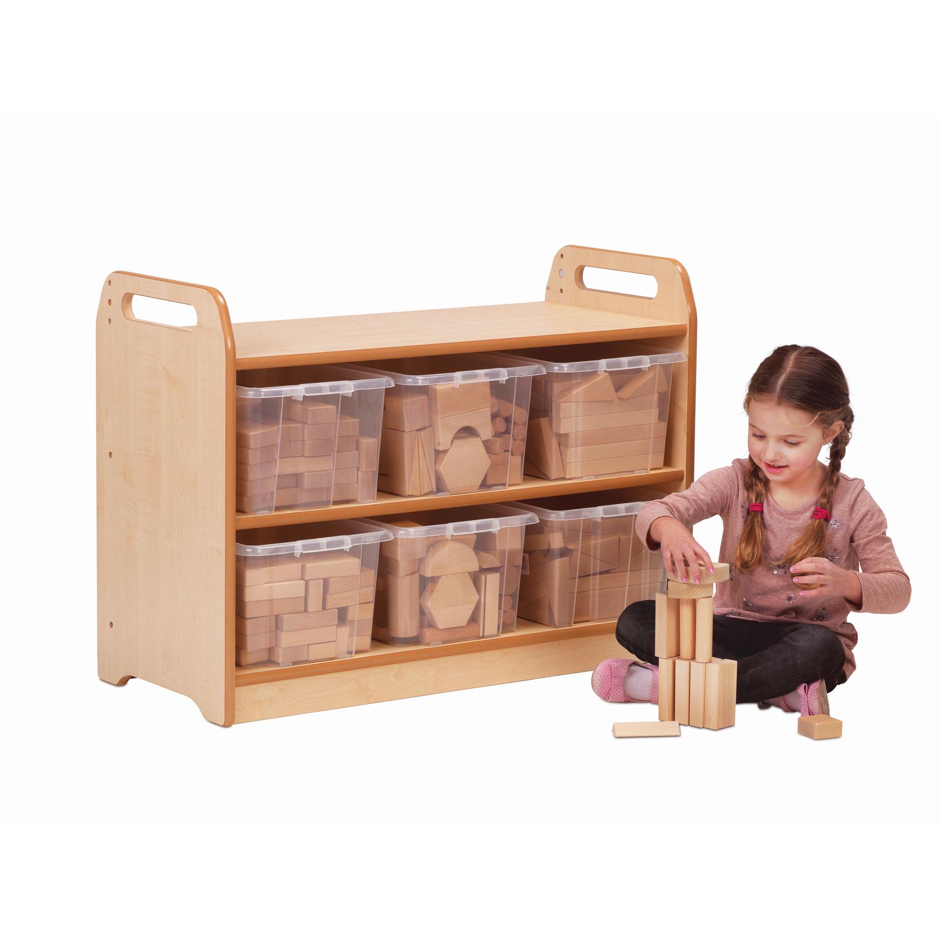 A young girl is building a tower from wooden blocks sat in front of the Block Play Unit with blocks neatly organised inside the six plastic tubs.  
