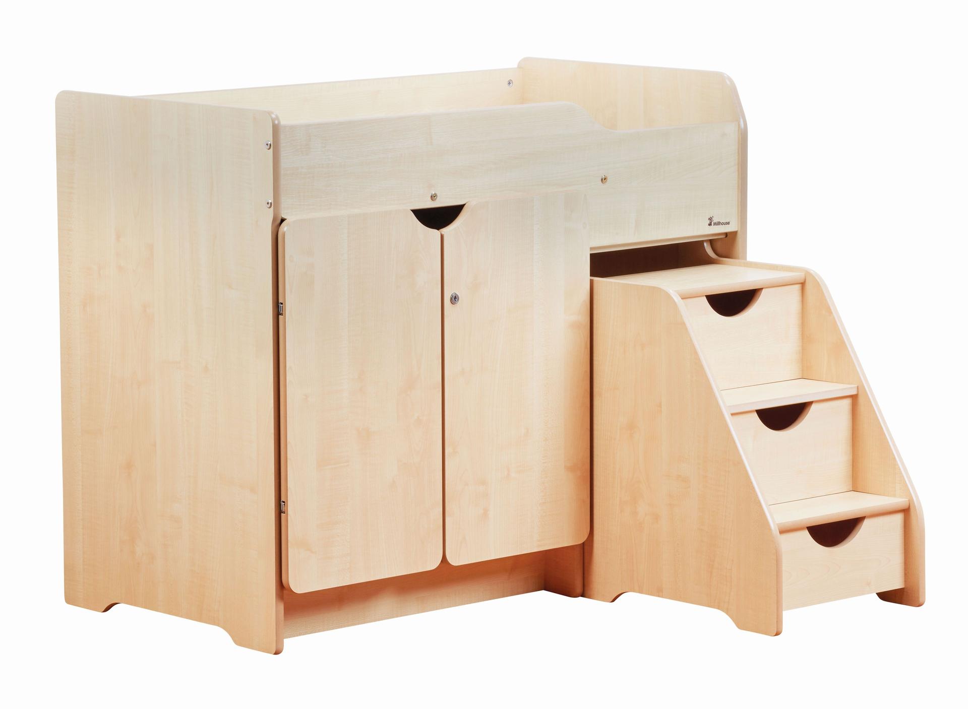 A toddler climbing up a wooden baby-changing unit with the help of an adult, within a nursery setting.