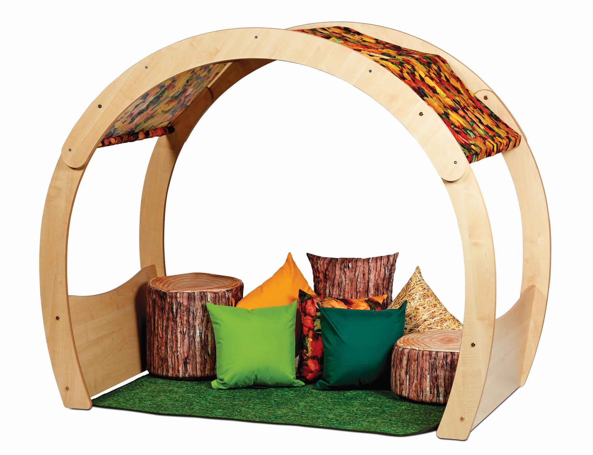 A wooden arch with tree-like fabric top, filled with cushions and blankets on the floor to sit on.