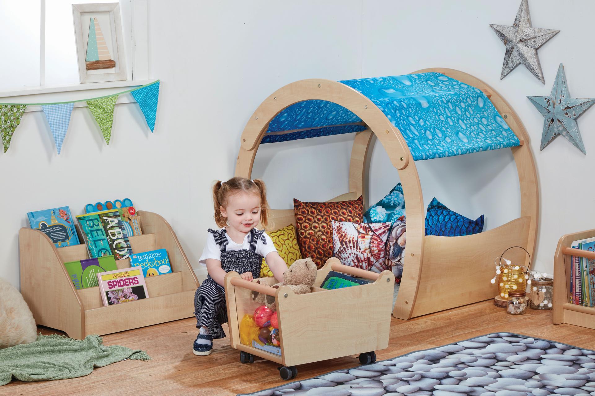 A young girl is using the book trolley in the Mini Under the Sea Zone, in the classroom.