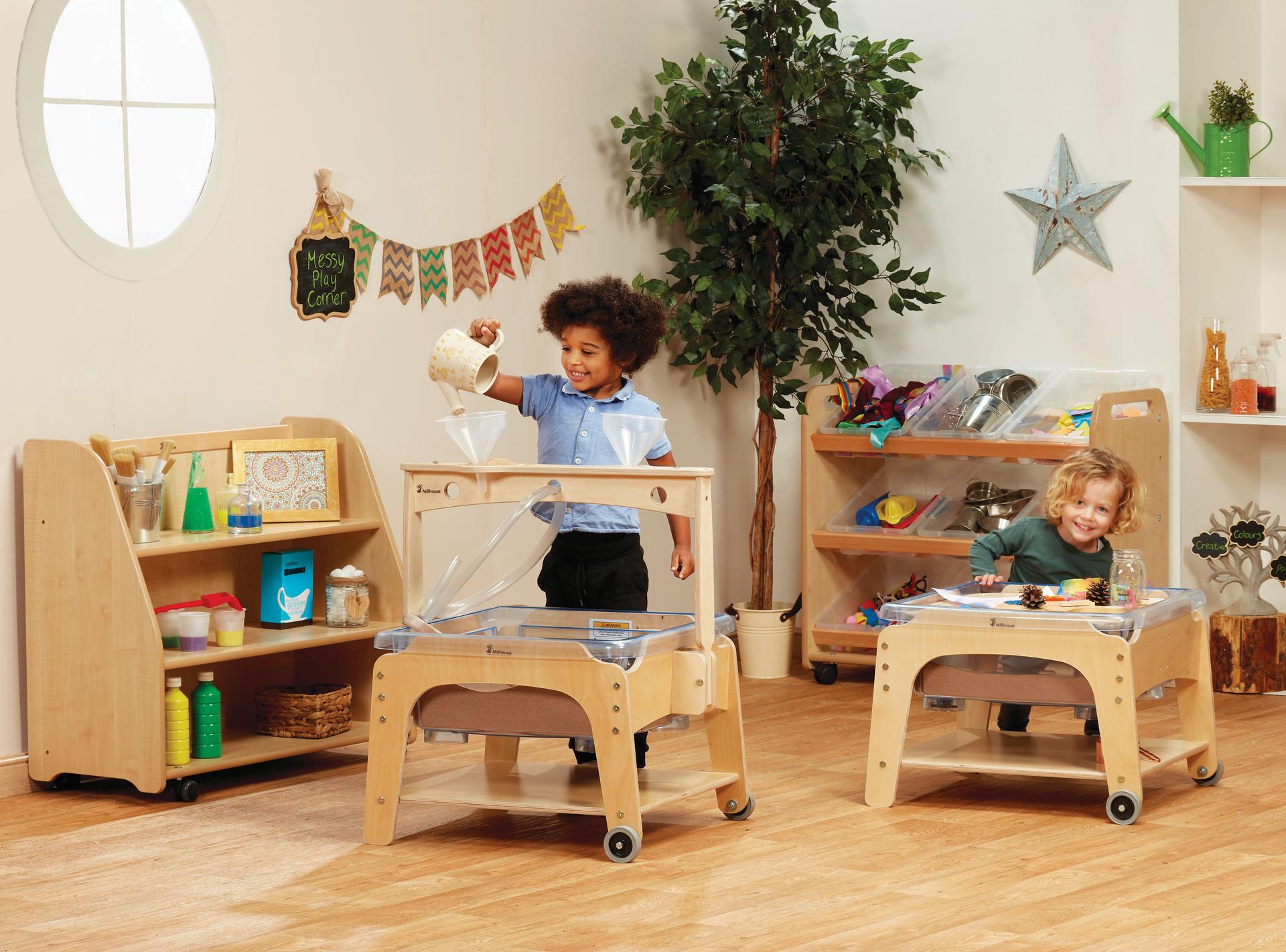 Two young boys are playing with the mini messy zone, in a classroom.