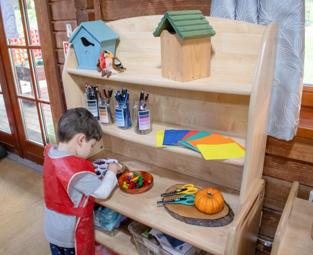 A child stood next to the Millhouse Welsh Dresser and sorting through his craft materials.