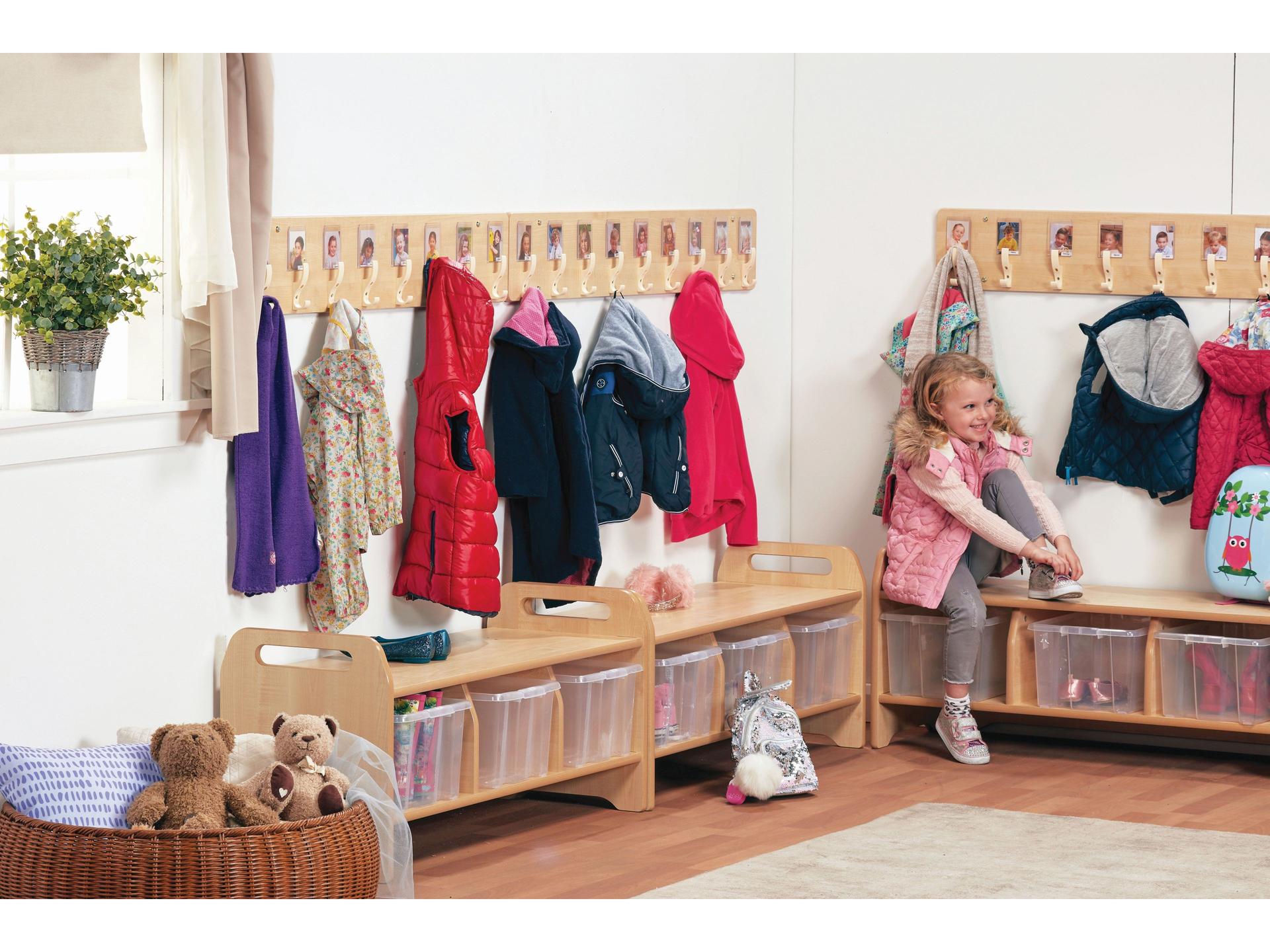 millhouse cloakroom set up with low storage and wall mounted hooks and child getting ready