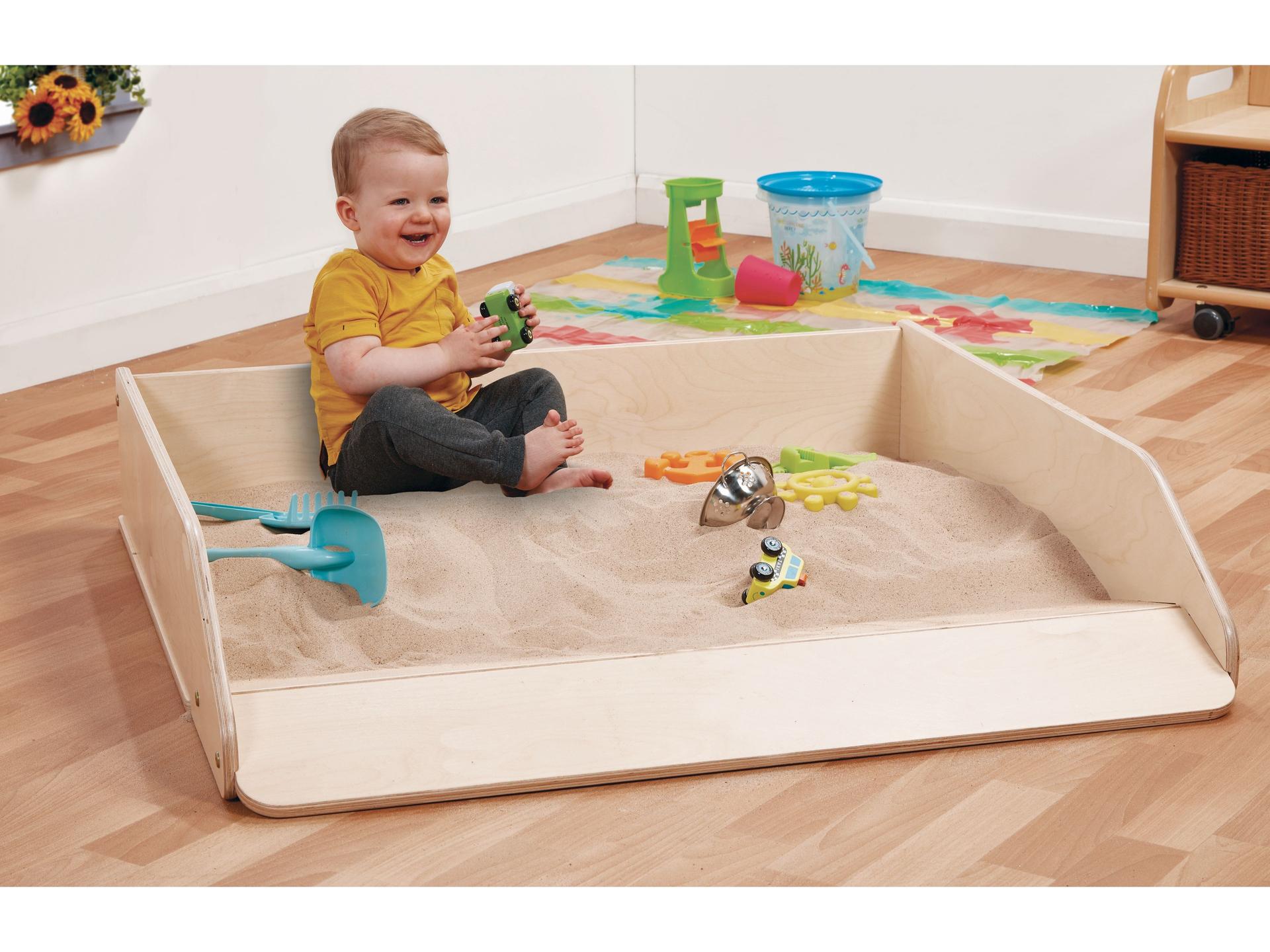 millhouse sand pit with baby playing in the sand and sand accessories surrounding