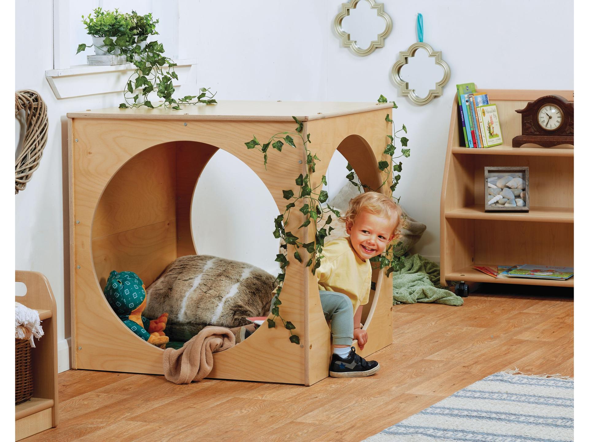 millhouse den with cosy items within and a natural feel, child climbing out