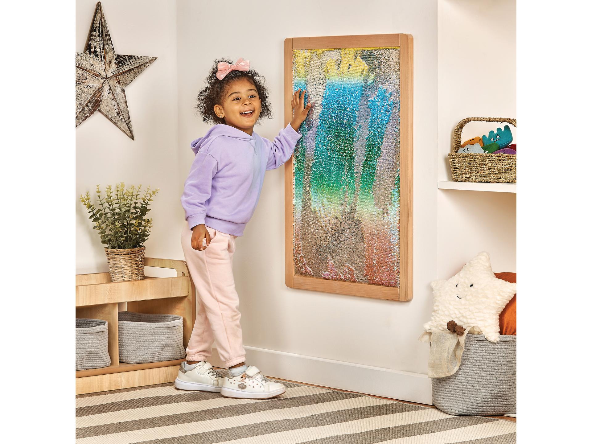millhouse sequin panel on wall with child brushing their hand up against