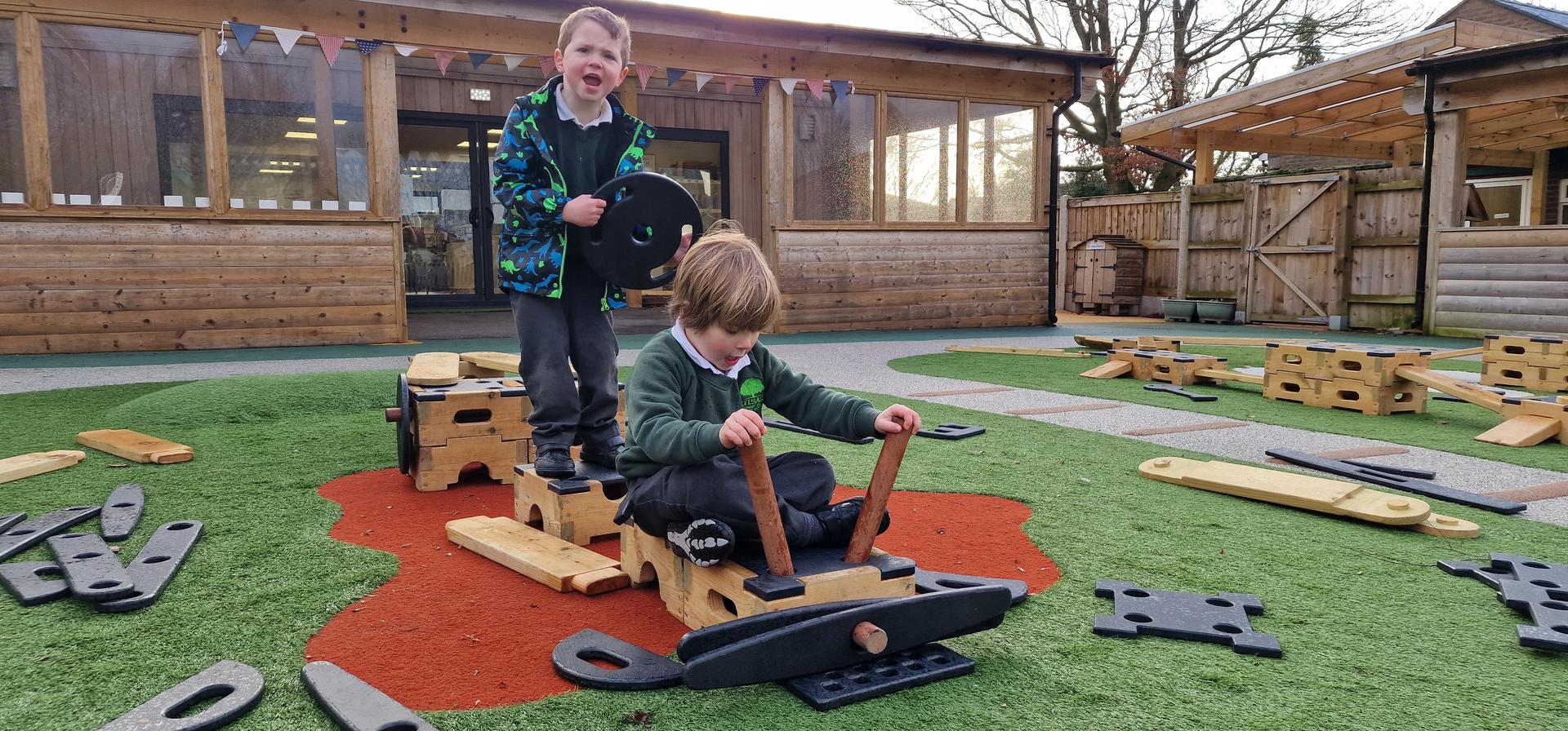 Two boys using planks and blocks to create a train
