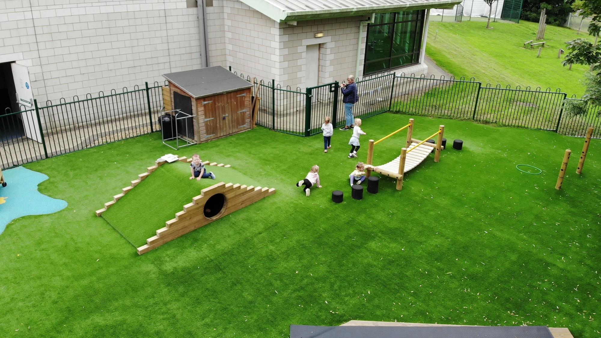 A bird's eye view of nursery childrne playing on artificial grass surfacing in their nursery garden