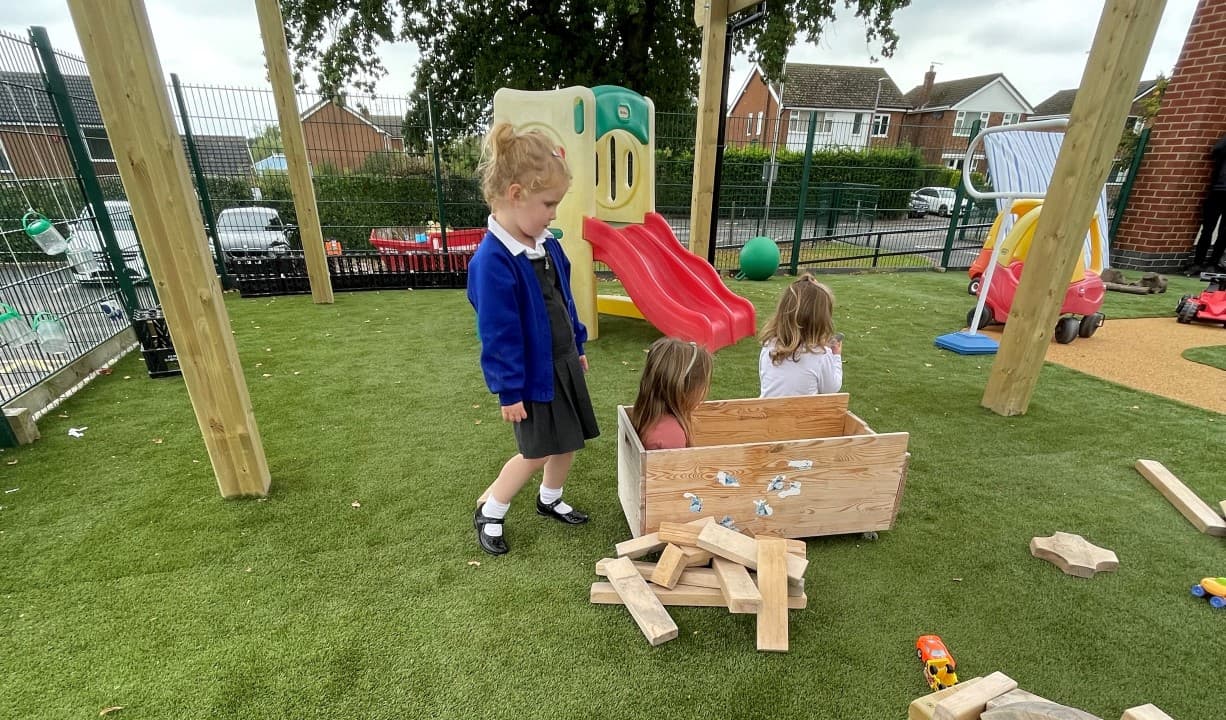 children play with wooden blocks on the artificial grass surfacing