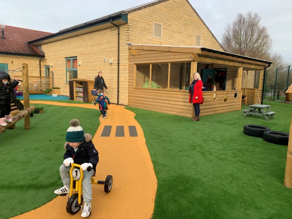 children go around the wetpour roadway on scooters