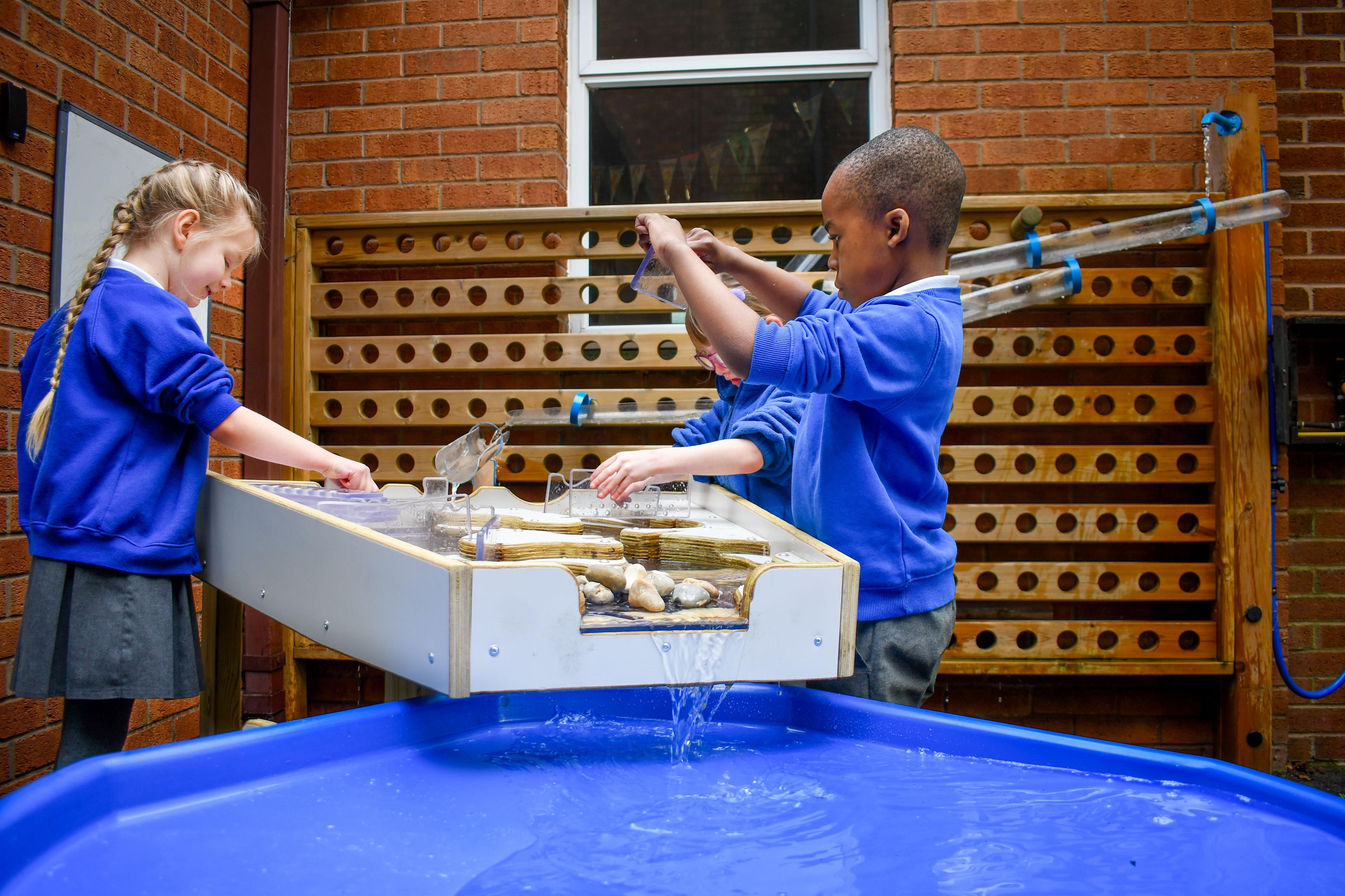 children playing with the damming station and tuff spot table