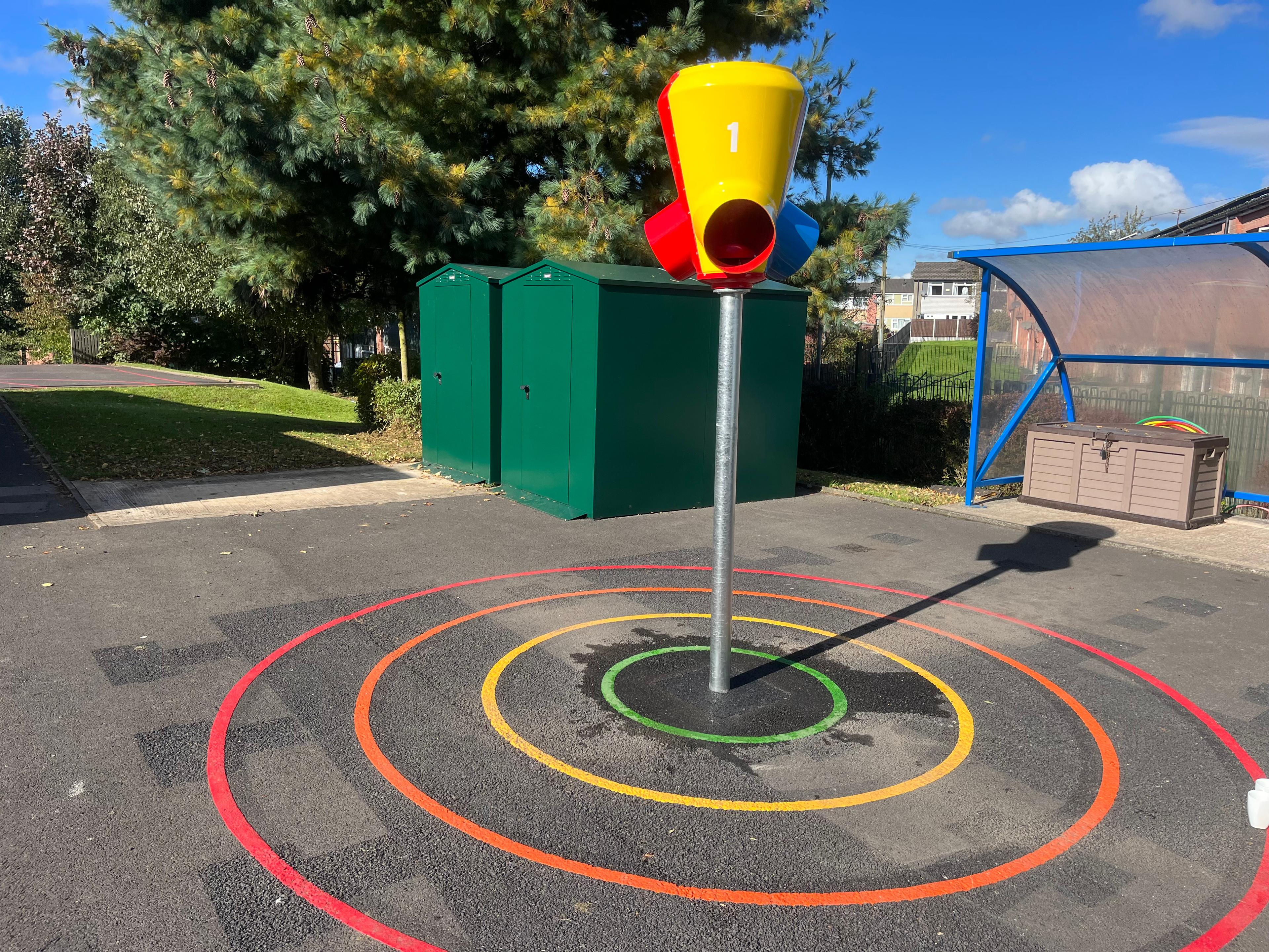 A 3-way ball shoot that has been installed on a tarmac playground with thermoplastic playground markings around it.