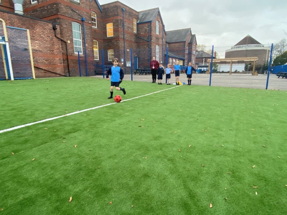 children play on the artificial grass surfacing used in a MUGA