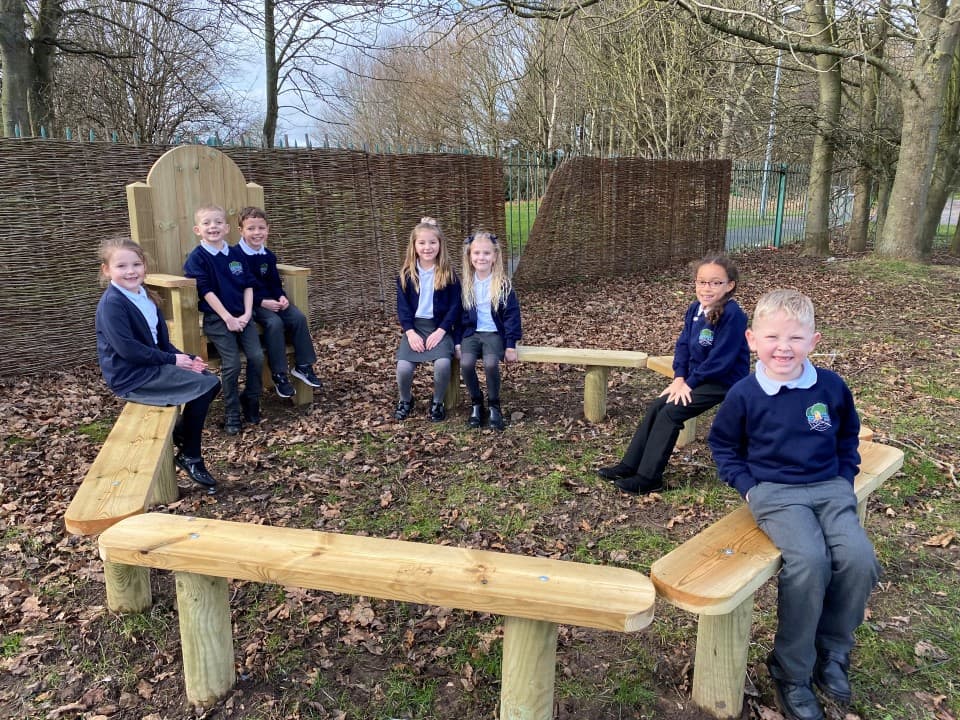 children sit around the perch benches and smile at the camera