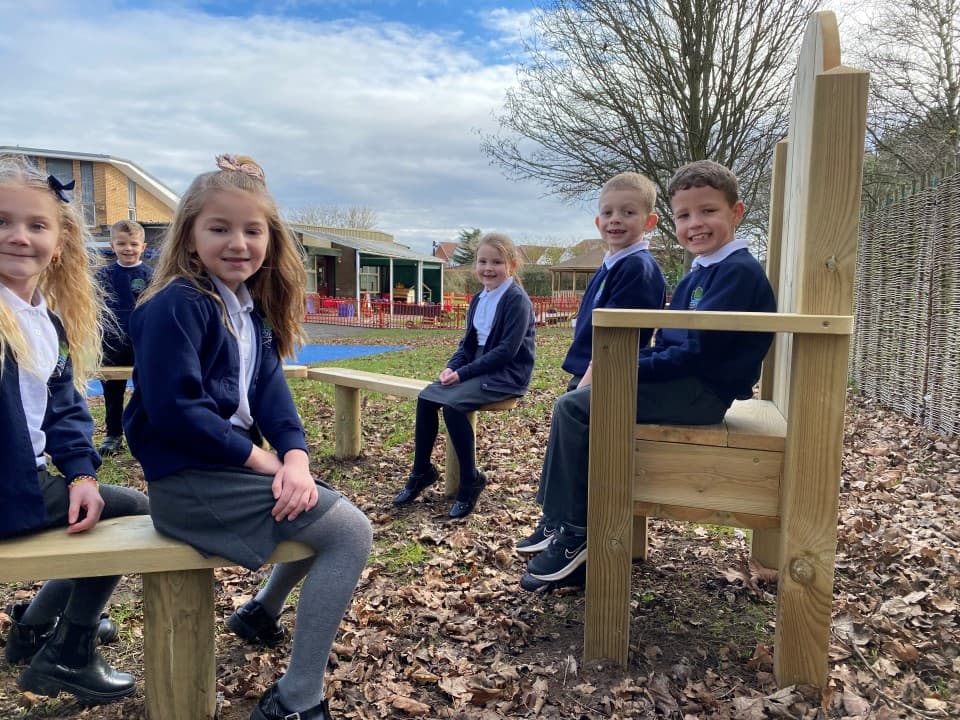 children sit on the story-telling chair and smile at the camera