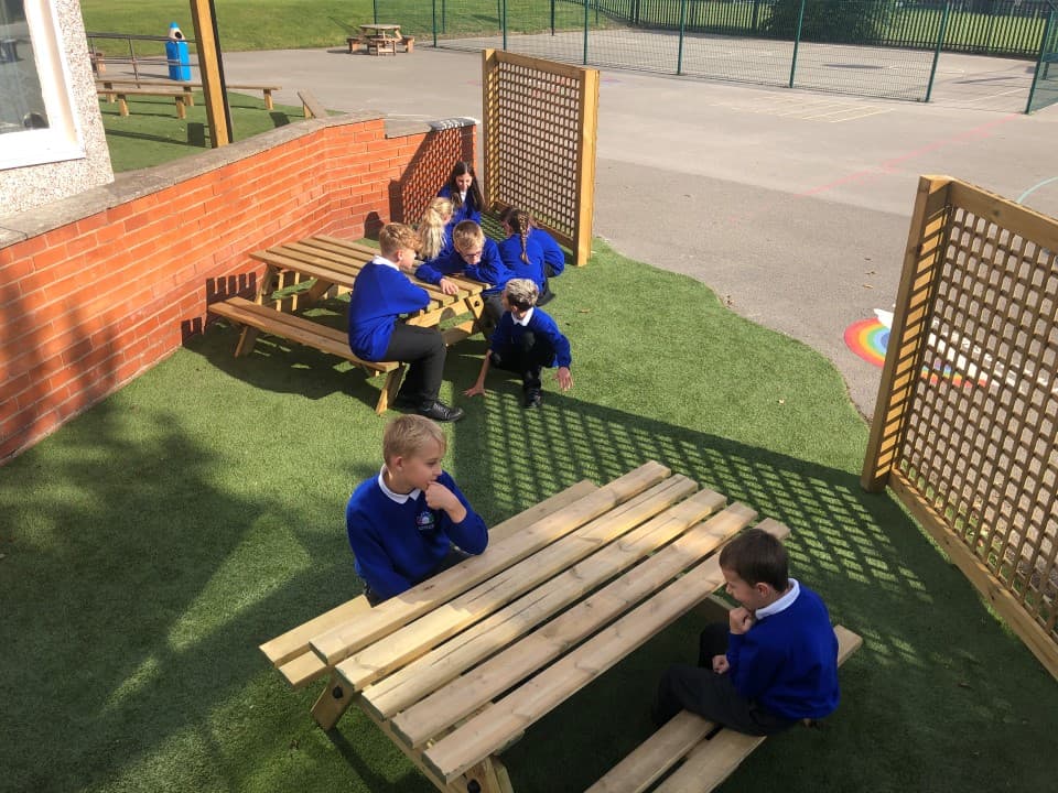 children gather and talk around a picnic table