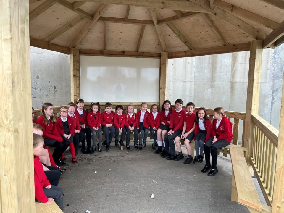 children sit inside the hexagonal gazebo