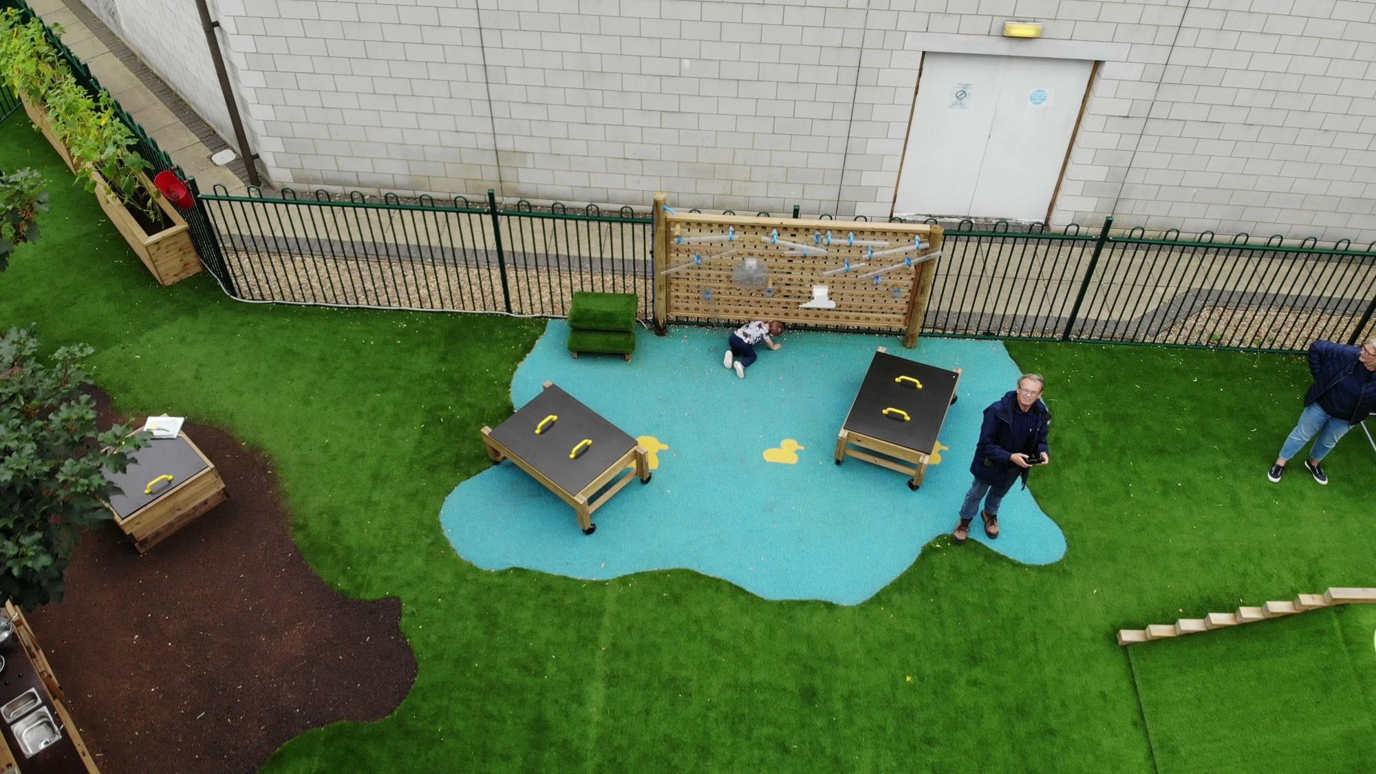 A blue wetpour splash cut into a section of artificial grass to create a zoned water play space