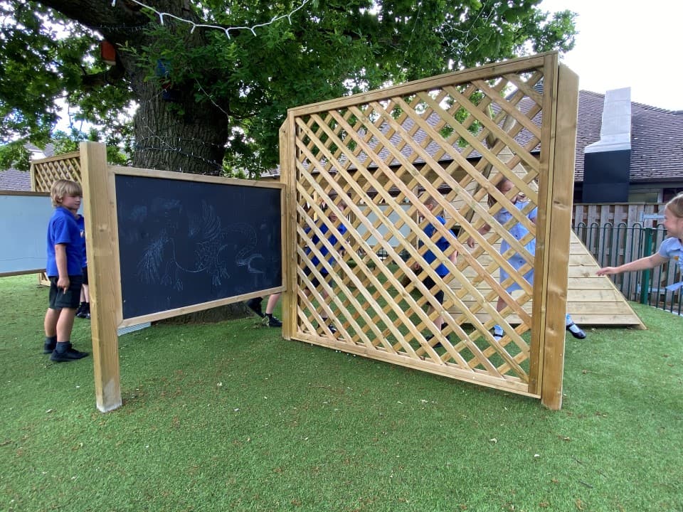 our weaver trellis standing in a school playground next to a giant chalkboard with children drawing on it