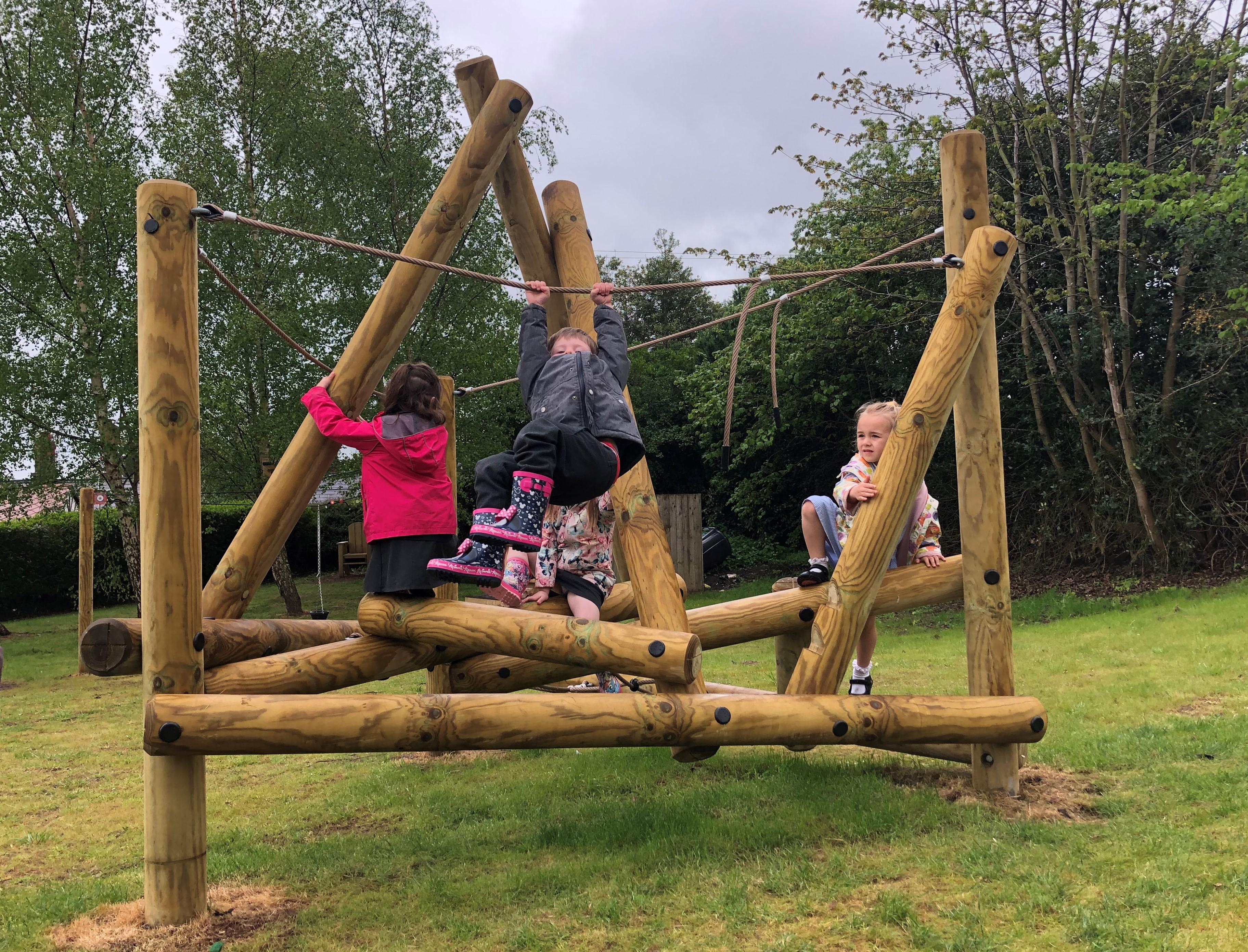 A class of children playing on the climbing frame in their playground