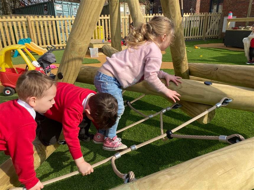 EYFS children playing on the climbing frame in their playground at school