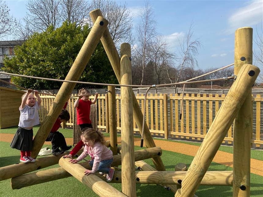 A class of children playing on the harterfell climber in their nursery setting