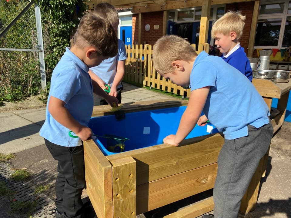 early years pupils playing with a water table