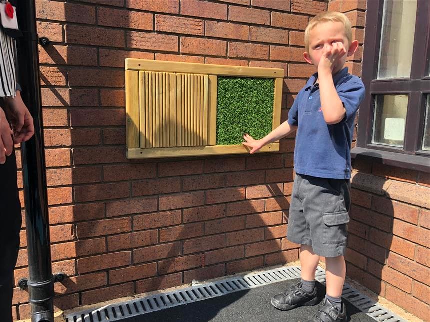 A boy playing with the sensory panel which is wall mounted