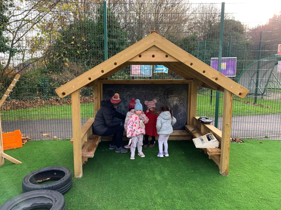 a giant playhouse with chalkboard and bench