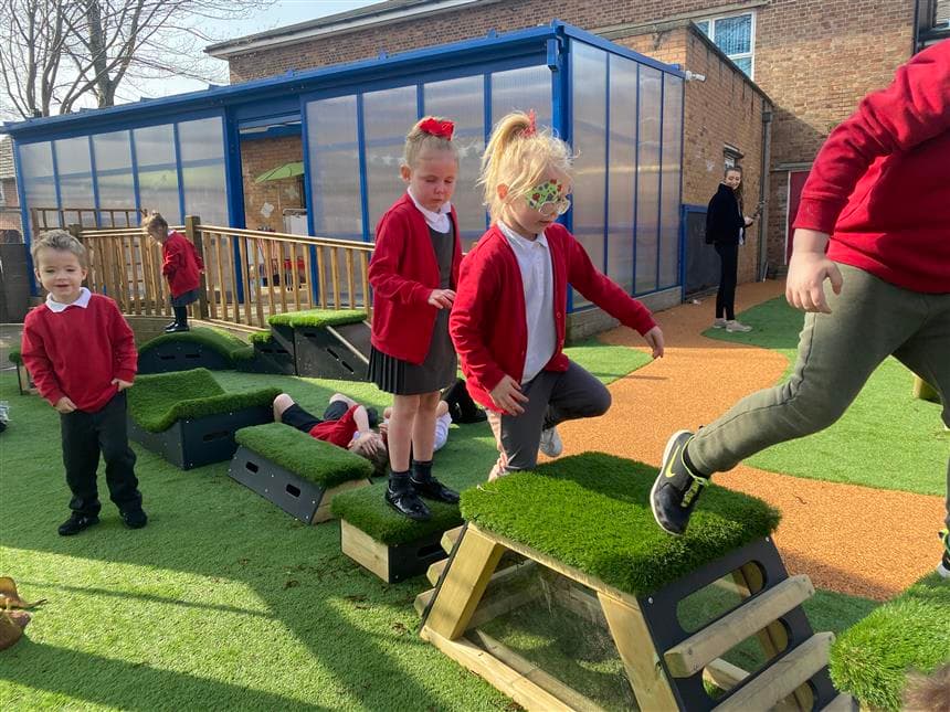 A class of children climbing across block to block on their get set go blocks.