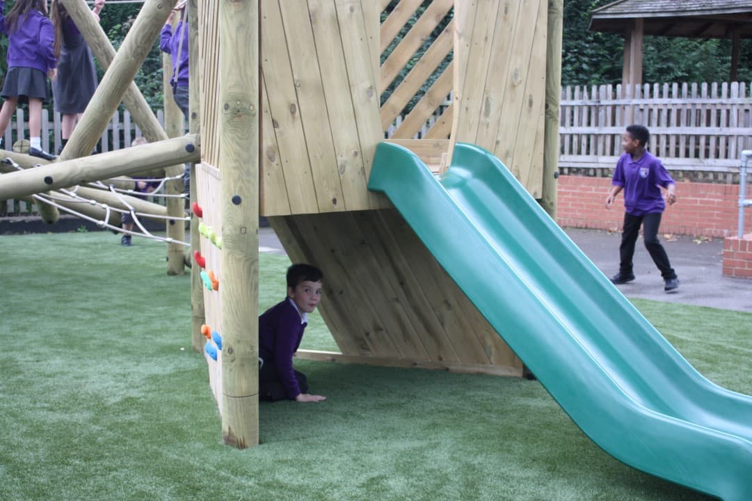 a green slide on the harter fell climber as a child hides in the crawl space under the frame