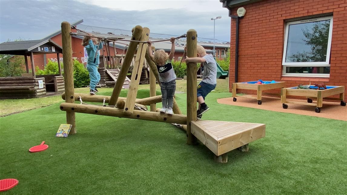 Early Years children playing on a climber in their playground