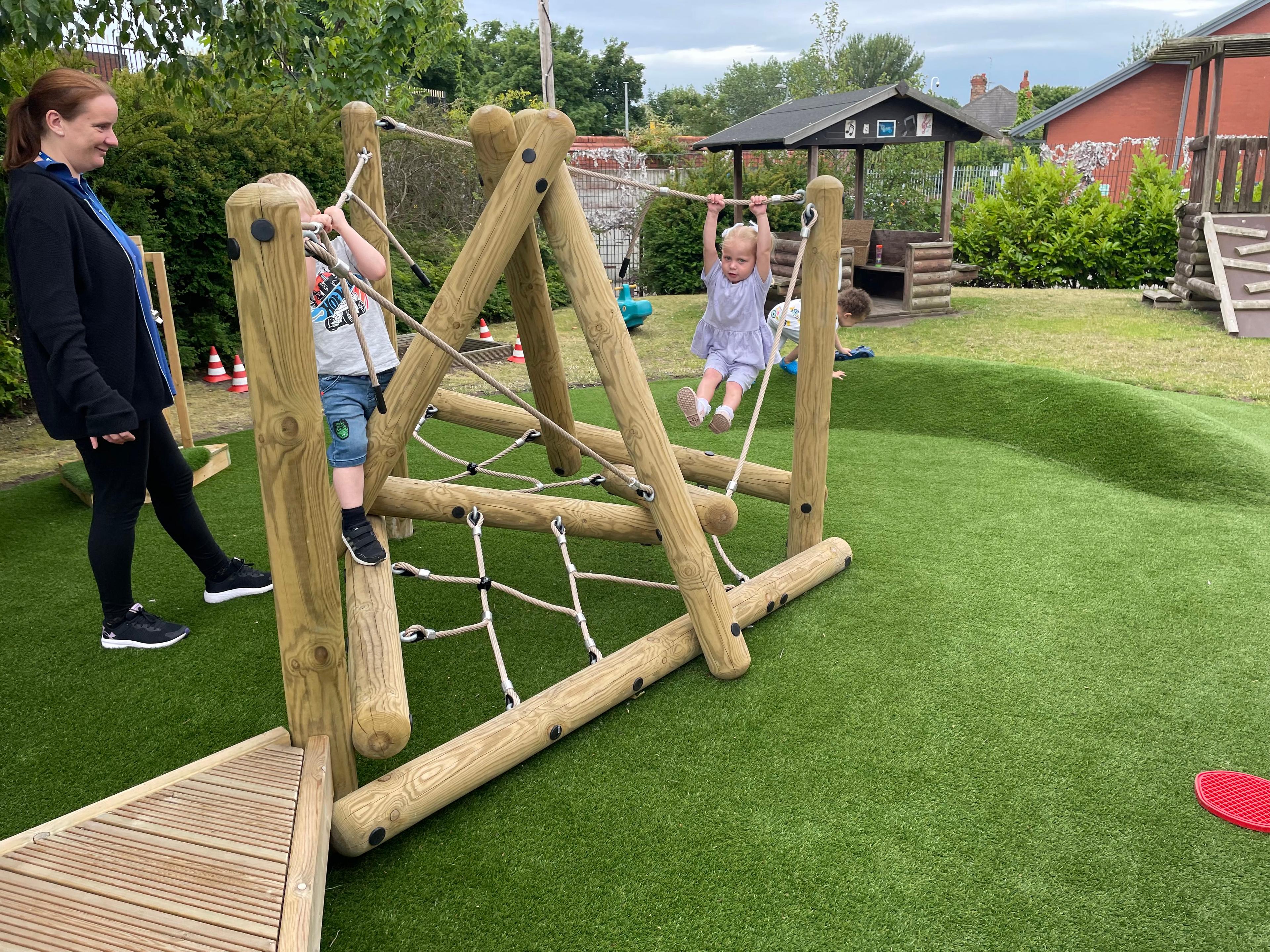 A early years class playing on the climbing frame in their playground