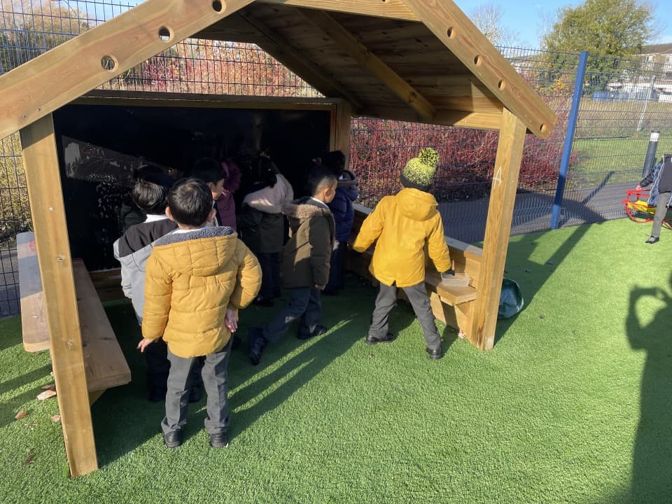 a small house being played in by pupils with a giant chalkboard