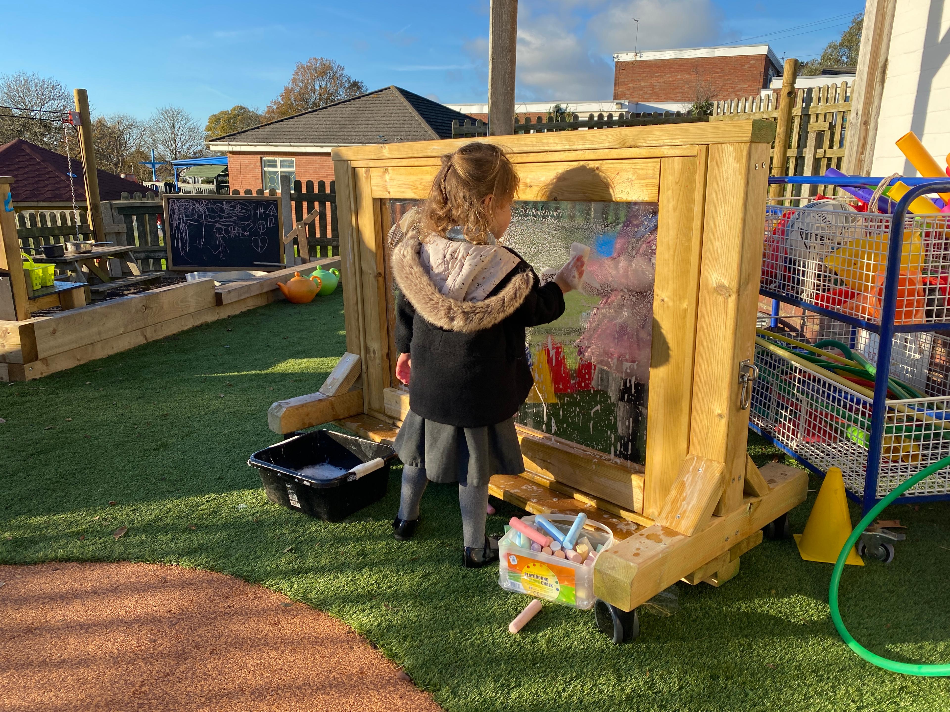 A girl using a sponge and soapy water on the paint panel.
