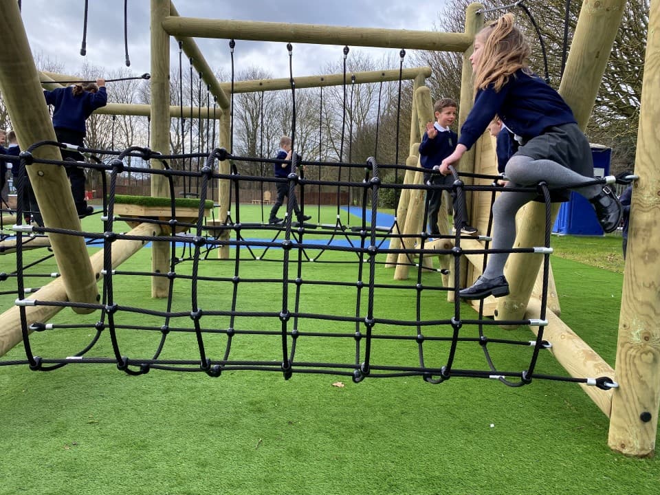 a little girl crosses the scramble net by going over the top