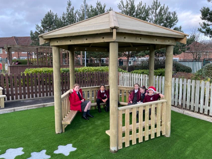 Children sat in a school playground gazebo