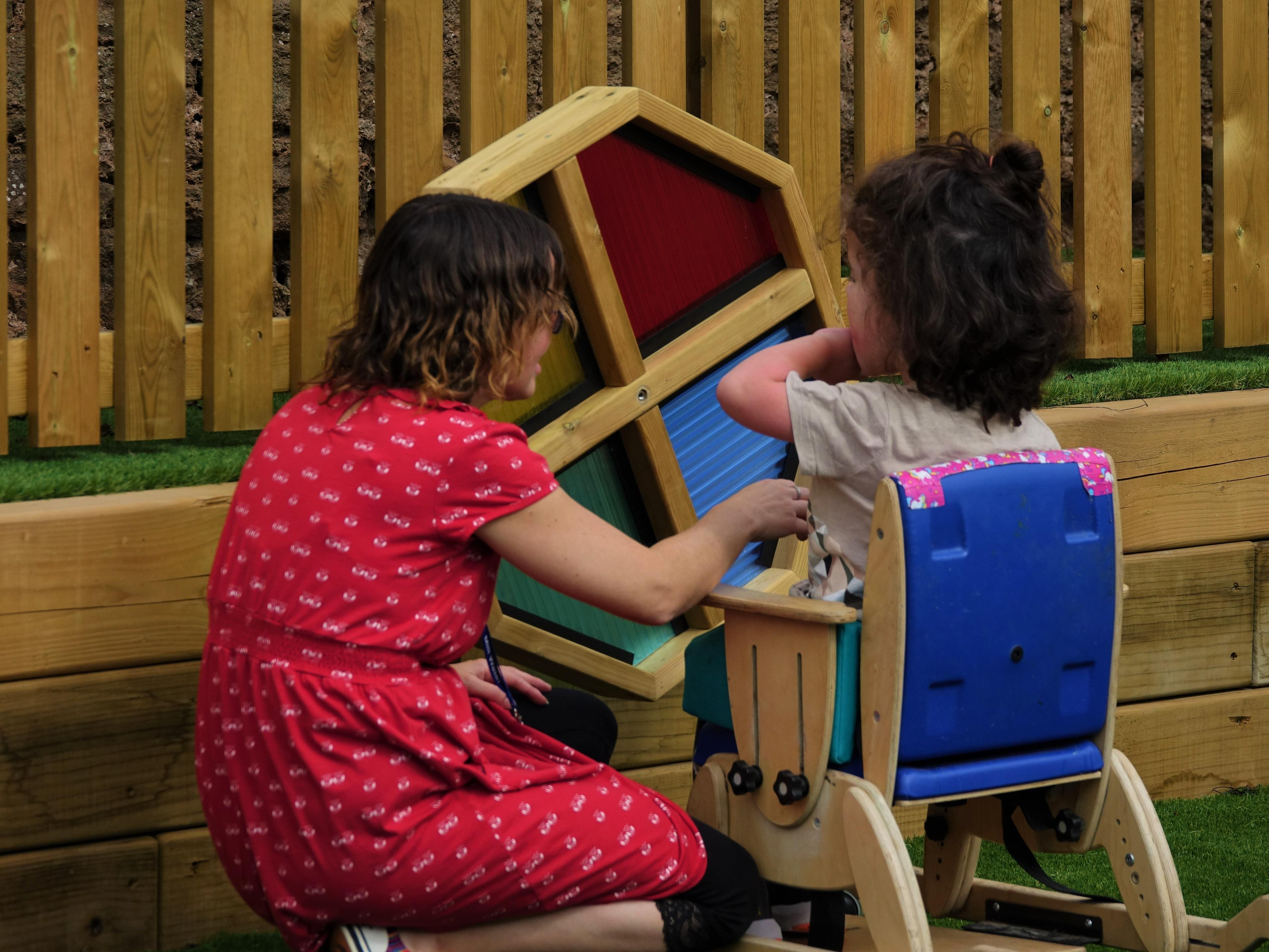 A young girl and her teacher are playing with the Sensory Spinner