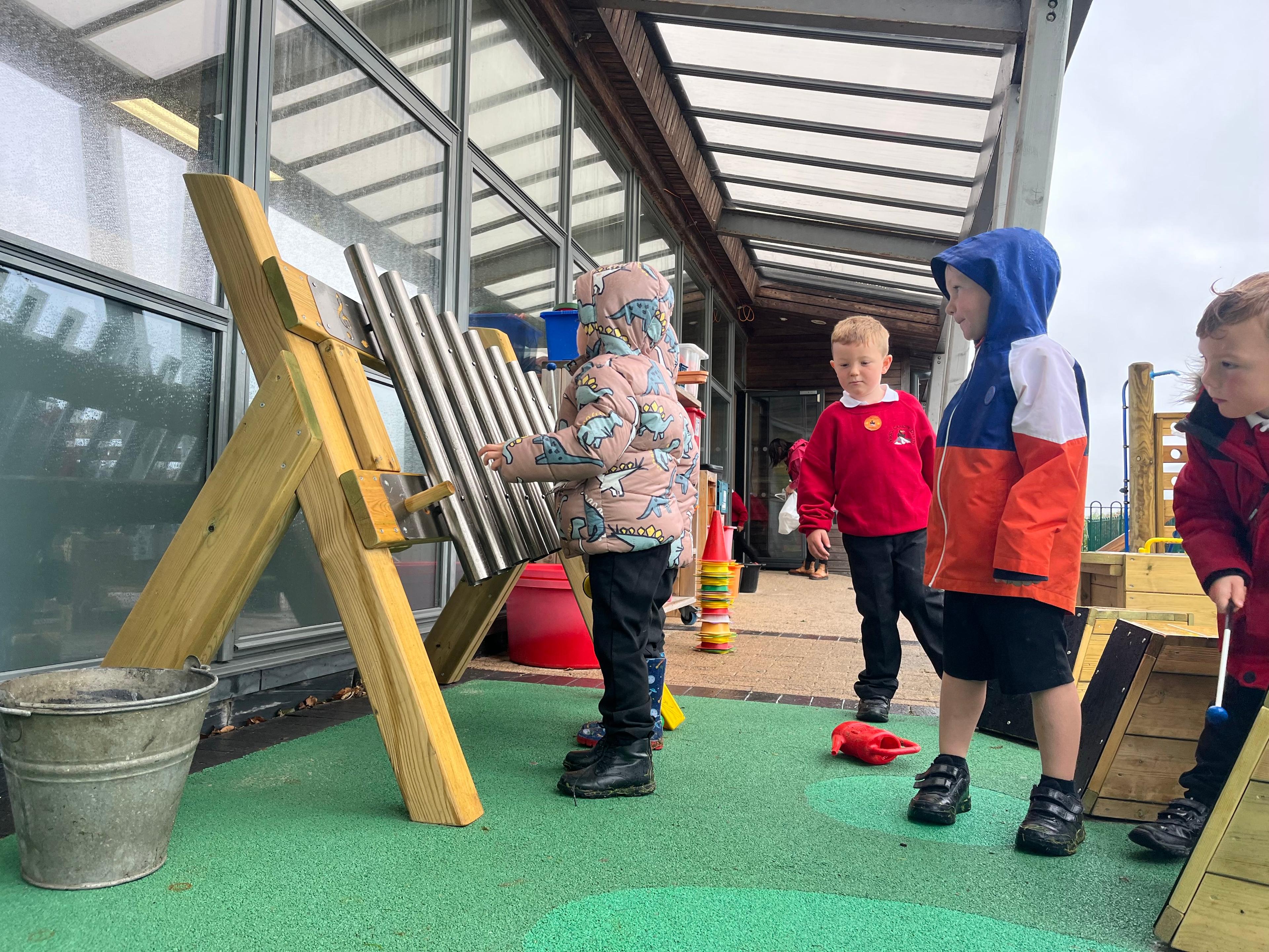 2 children playing the freestanding chimes in their playground