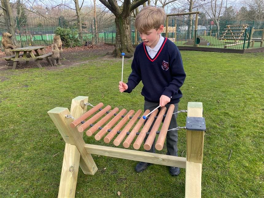 one young boy playing on the marimba in his playground