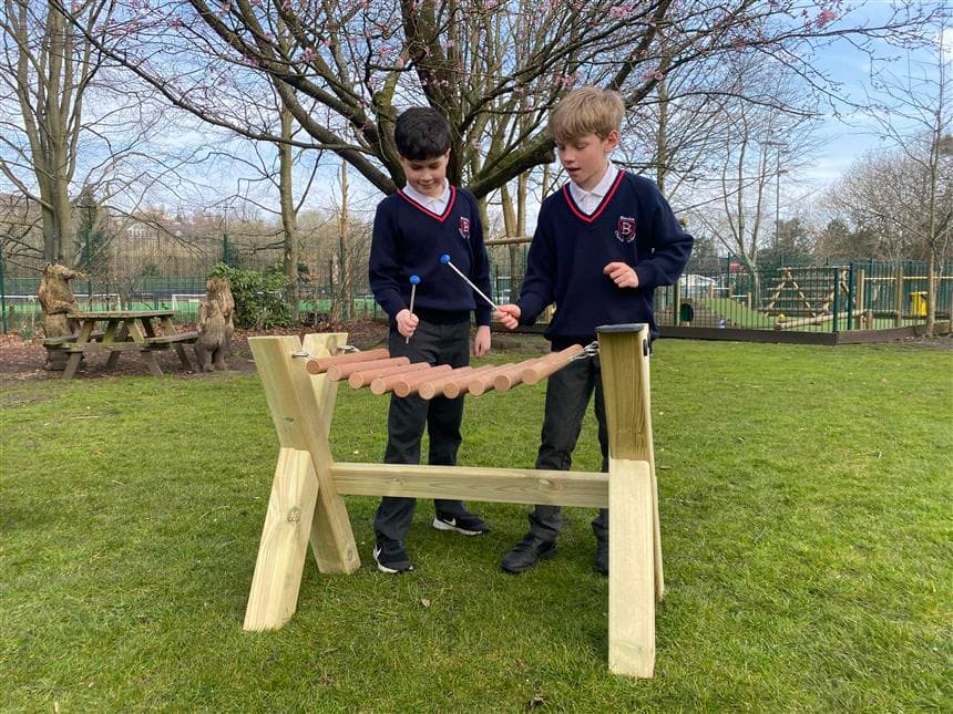2 children playing on the marimba in the school playground