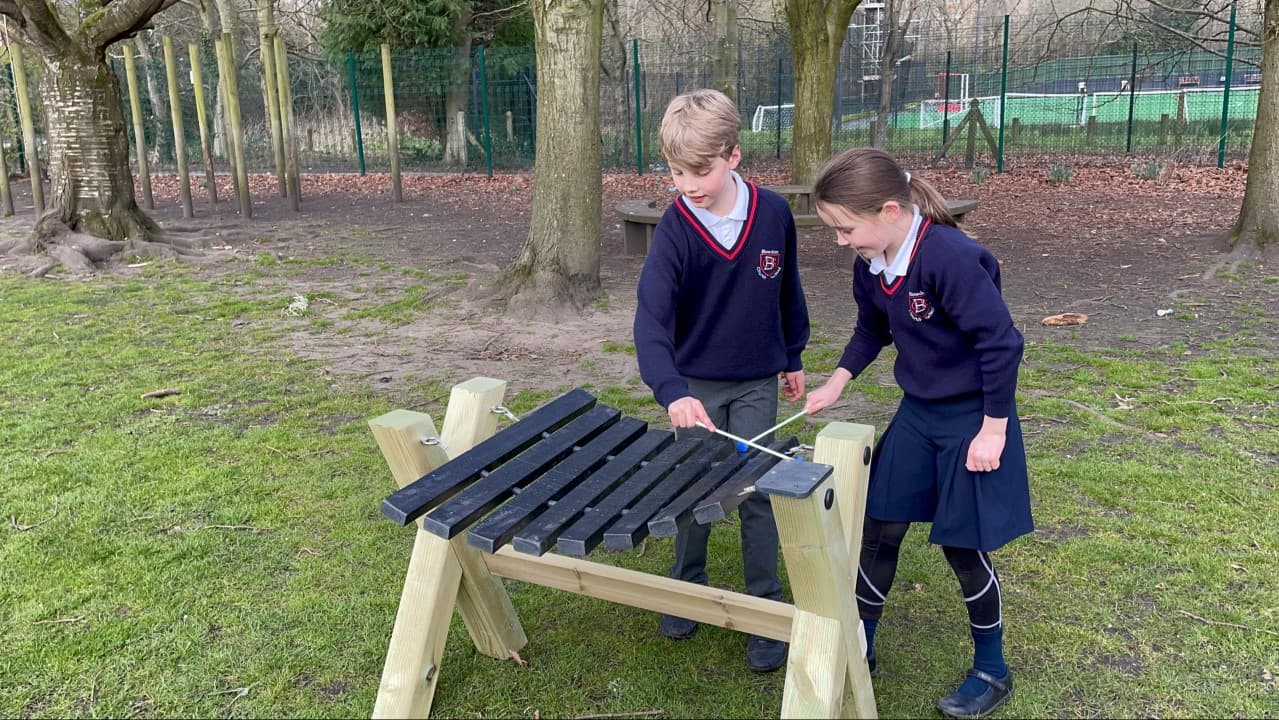 two little children stand behind the xylophone